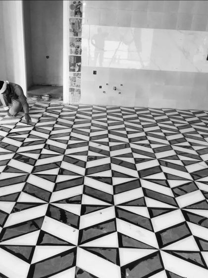 A work-in-progress shot of a super cool geometric floor pattern being laid. This intricate black and white marble inlay required precision and skill, resulting in a 3D-effect pattern that is both modern and visually captivating.
