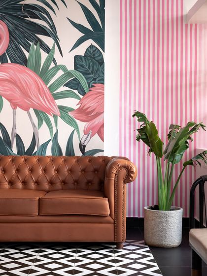 The reception area sets the tone for the 'Pink Verranda'. I commissioned a hand-painted flamingo mural as a bold focal point, pairing it with a classic brown leather chesterfield sofa and geometric flooring for a playful yet sophisticated welcome.