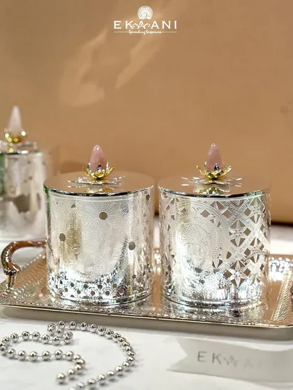 Soft glows, intricate details, and a touch of divinity. This beautifully engraved silver tea light holder is elegantly enhanced with a rose quartz stone on top, adding charm and warmth to any corner.