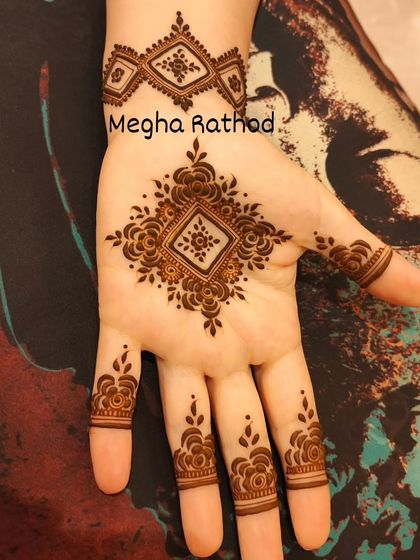 A perfect example of minimalist mehendi, this small, geometric design on the palm with simple finger rings is chic and modern.