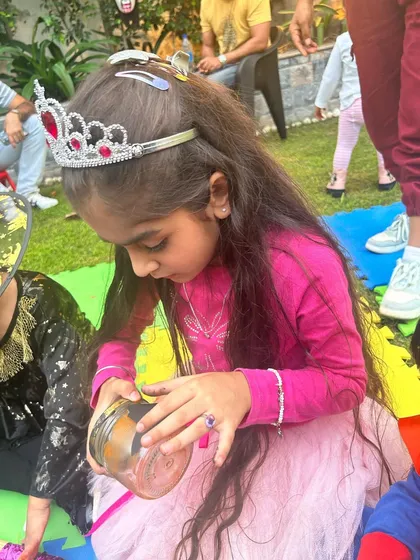 Even princesses love a good craft session. A young girl dressed in a tiara is completely absorbed in a creative activity during our fun-filled Halloween party.