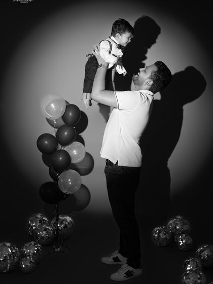 A playful black and white shot of a dad lifting his son high. The dramatic lighting creates a powerful and joyful silhouette.