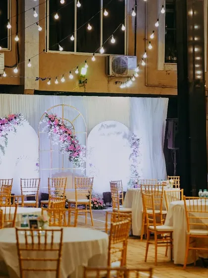 The full view of our outdoor setup for a 78th birthday. The combination of the beautifully lit stage, round table seating, and overhead lights created a festive and cohesive atmosphere for all the guests.