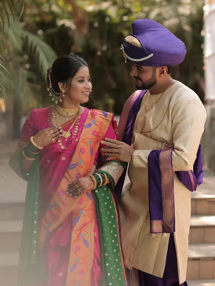A beautiful couple portrait. The bride is dressed in a traditional pink and green Nauvari saree, her makeup soft and glowing.