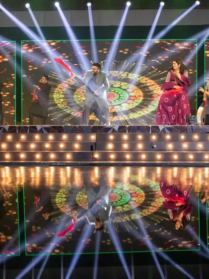 A wide shot of the groom's performance, showcasing the grand scale of the stage, lighting, and LED backdrop we can arrange for your sangeet.