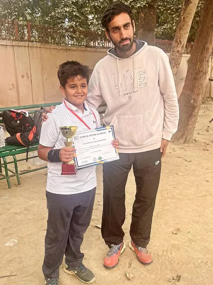 A young champion from our Dwarka center stands with his coach after winning the U6 category at an open tennis tournament in Delhi. His trophy and certificate mark the start of a promising journey.
