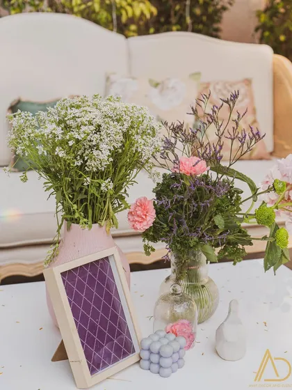 A delicate and pretty tabletop arrangement with fresh flowers in glass vases and a small, patterned picture frame, creating a soft, romantic vibe.