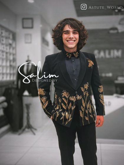 A young client in a black velvet tuxedo with gold floral embroidery. This design is elegant and timeless, perfect for any formal celebration.