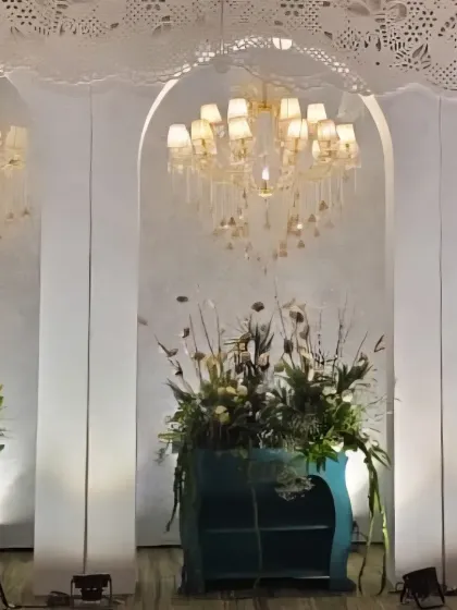 A wide view of the stage area, showcasing the combination of white architectural elements, teal accents, and abundant white florals.