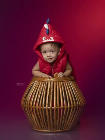 Roar! A cute baby wearing a red dinosaur hoodie peeks out of a wicker basket. This fun and imaginative shot is perfect for showing off a child's playful side.