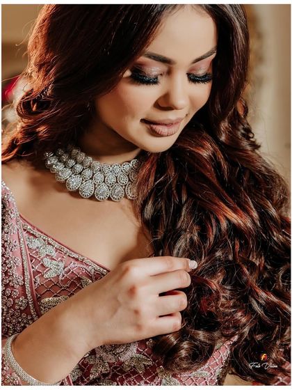 A close-up portrait of the bride from her engagement, focusing on her soft makeup and sparkling diamond necklace.