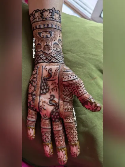 This design features two peacocks facing each other, surrounded by delicate vines and topped with an elephant cuff.