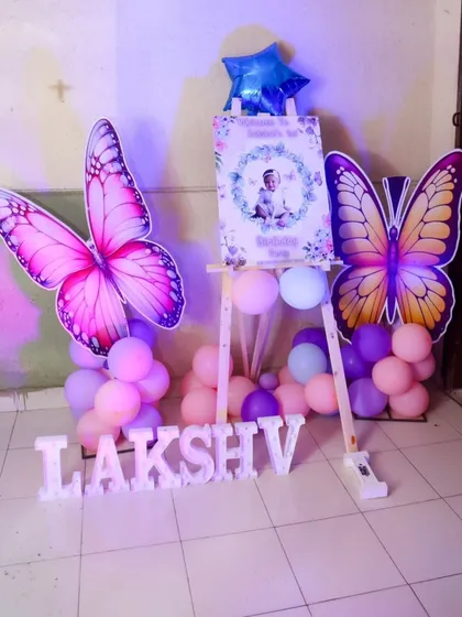 A beautiful welcome sign on an easel for a butterfly-themed birthday, flanked by large butterfly props.