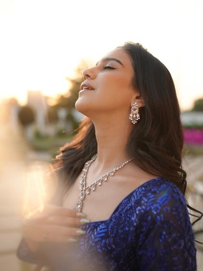 A close-up portrait in the blue sequin lehenga, focusing on the delicate diamond necklace and the soft evening makeup.