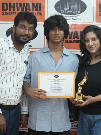 A student, his mother, and his teacher pose together with his trophy.