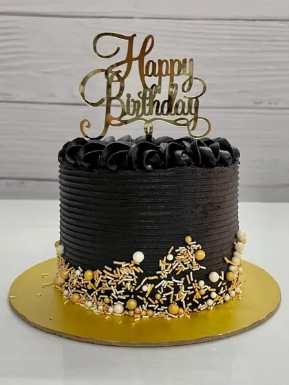 A simple yet elegant black chocolate cake with gold sprinkles, perfect for celebrating the hero in your life.