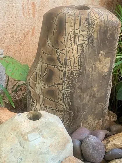 This two-piece stone fountain has a lovely, weathered texture that blends beautifully with the surrounding peace lilies and papyrus plants. It's a great example of a compact fountain that makes a big impact.