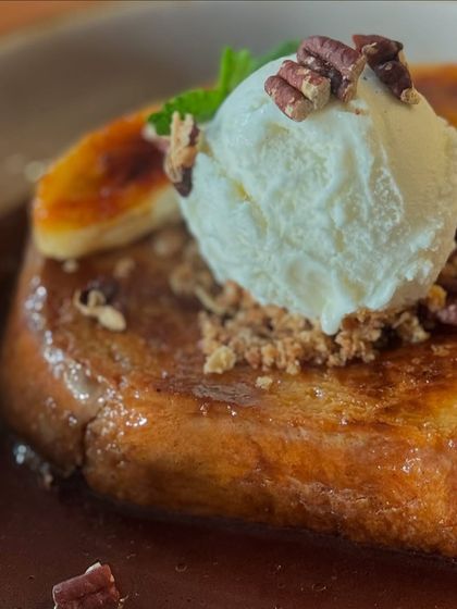 Crafted for indulgence, our brunch sweets are the perfect finale. This is our Pain Perdu, a decadent French toast with caramelized banana, rum chocolate anglaise, and vanilla bean ice cream.