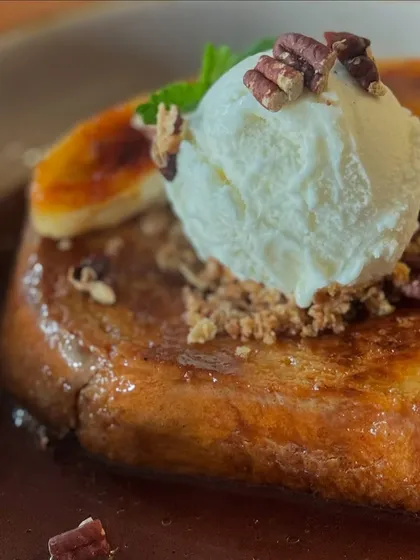 A close-up of the Pain Perdu, topped with vanilla ice cream, toasted pecans, and caramelized banana.