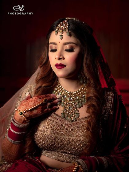A beautiful bridal portrait with dramatic red lighting, highlighting the rich color of her velvet lehenga and her flawless makeup.
