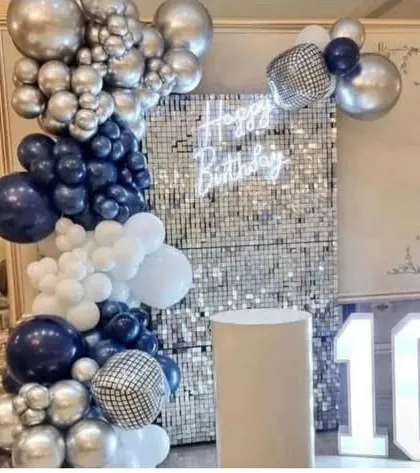 A 10th birthday party with a silver sequin wall. The decoration features a balloon garland in navy blue and silver, with disco ball accents and a marquee number '10'.