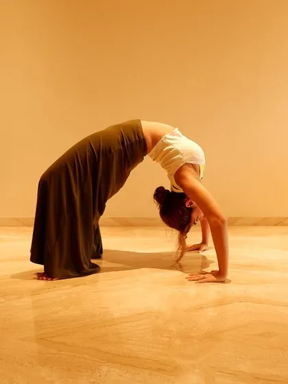 A deep backbend in the wheel pose. This is an advanced yoga posture that demonstrates incredible flexibility and strength, essential for a dancer's body.