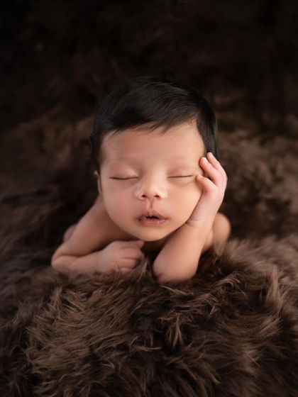 A different angle of the classic 'froggy' pose, showcasing the baby's peaceful expression while resting on a soft, furry blanket.