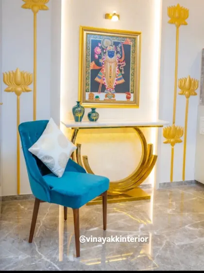 This corner is a blend of spirituality and modern luxury. A traditional Pichwai painting of Lord Krishna is the focal point, complemented by a golden console table, lotus wall art, and a vibrant teal accent chair.