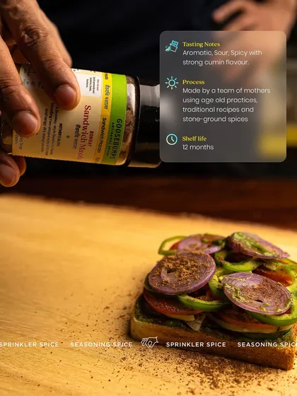 A hand sprinkling my Bombay Sandwich Masala over layers of fresh vegetables. This shot highlights the process and the key details: it's an aromatic, sour, and spicy blend made by mothers using traditional practices.