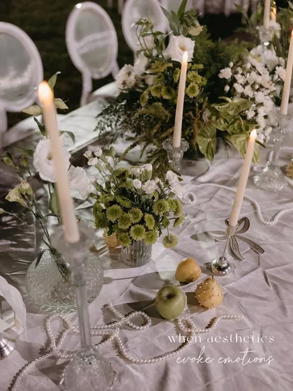 A beautiful tablescape detail, with fresh apples and pears scattered among strings of pearls and glowing candles.