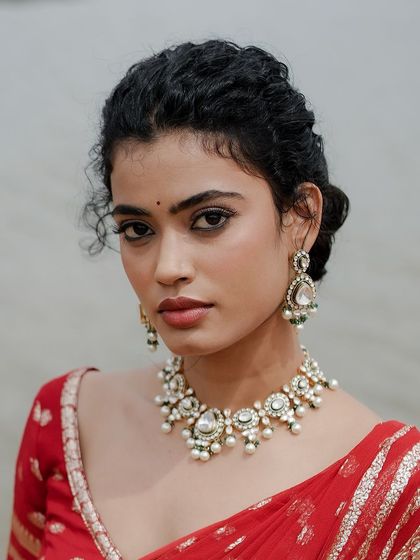 A close-up of the makeup, which is kept clean and classic to let the red saree be the hero.