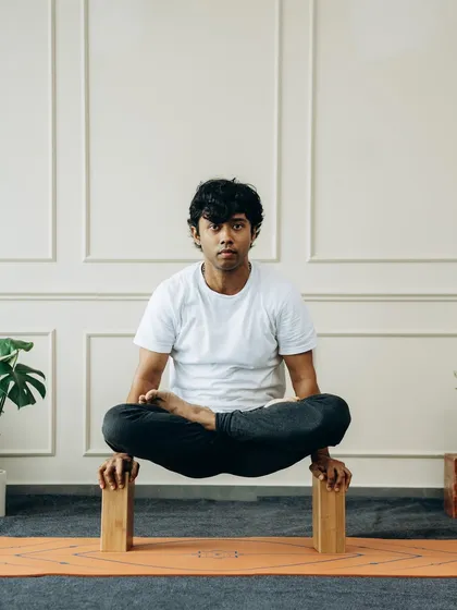 This is Tolasana (Scale Pose) with the support of blocks. Using blocks under the hands provides the necessary lift to raise the body, teaching the principles of balance and core engagement in a supported way.