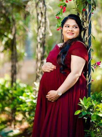 A serene solo maternity portrait in a garden pathway, surrounded by greenery.