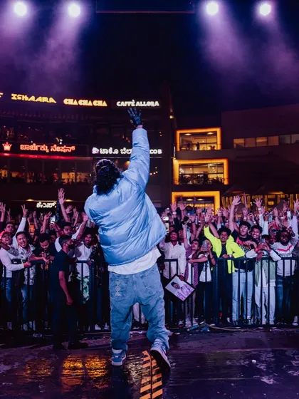 An artist connecting with a massive audience at an outdoor mall venue. We are adept at transforming public spaces into vibrant concert venues, managing stage setup, sound, and crowd interaction.