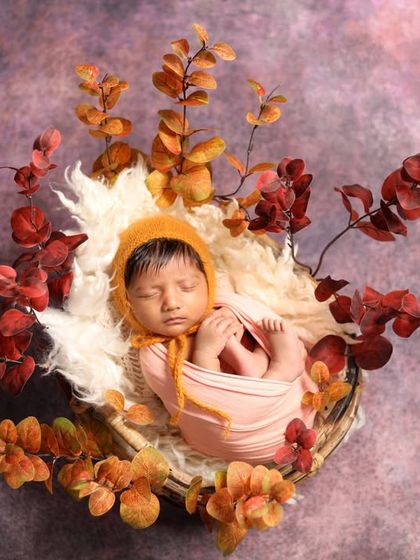 This little one is nestled in a basket with warm, autumn-colored leaves. I love creating seasonal themes that feel so cozy and special.