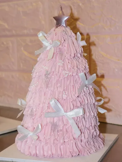 Another view of our playful pink Christmas tree cake, topped with a star candle for the perfect holiday wish.