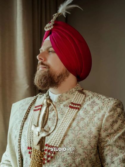 A close-up profile shot of Samuel, highlighting his handsome features and the details of his traditional Sikh groom attire.
