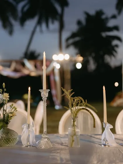 A simple and elegant table setting at a Goa event, with candles and small floral arrangements creating a romantic and intimate atmosphere.