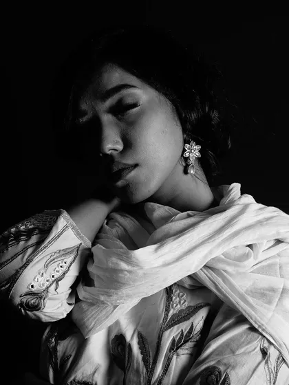 A moody black and white portrait where the light gently falls on one side of the model's face. The soft focus and shadows create an intimate and soulful image.
