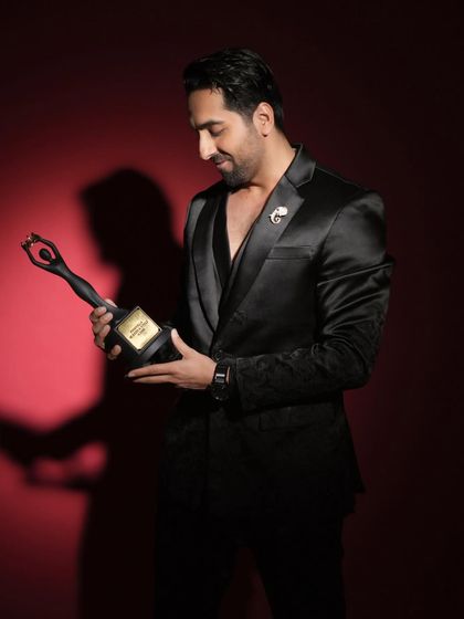 A shot of Ayushmann Khurrana with his award for Pinkvilla. The lighting is kept dramatic and celebratory.