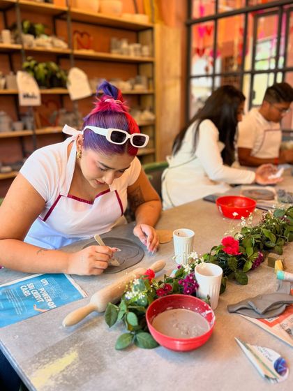 The studio is decorated with flowers and love for our Valentine's workshop, where a participant gets creative with her plate design.