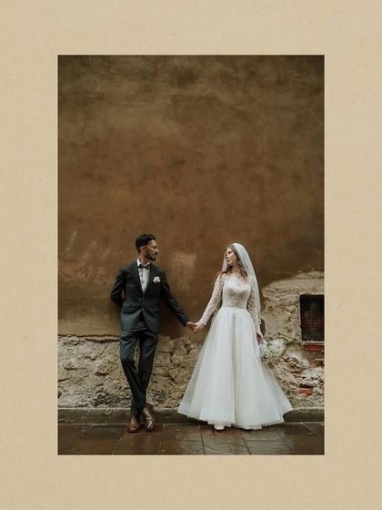 A romantic, artistic shot of the couple holding hands against a rustic European wall. It highlights the quiet, intimate moments of their international love story.
