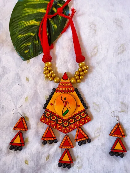 This triangular pendant features a hand-painted tribal dancer against a sunset-hued background. The geometric shape and folk-art motif create a beautiful fusion, perfect for those who love artistic and ethnic jewelry.