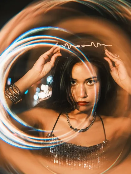 A creative portrait where the model is adjusting a snake-like headband. I used a special filter to create a circular light trail effect, giving the image a magical and dynamic quality.