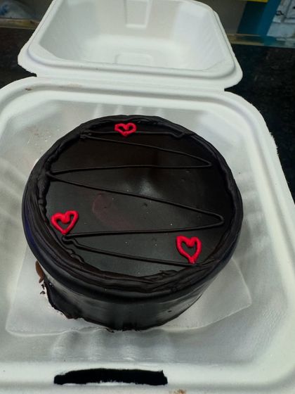 A rich chocolate bento cake with simple red heart decorations. It's a classic choice for a quick and delicious celebration for any chocolate lover.