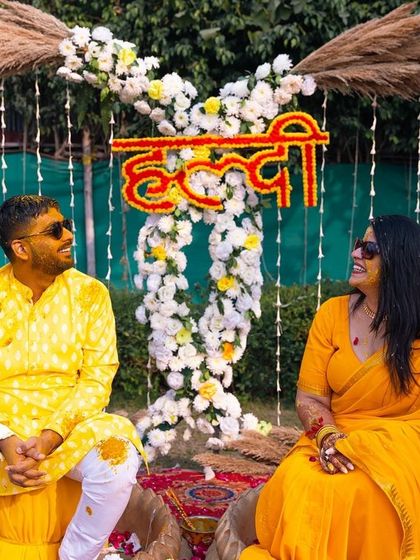 A happy couple posing at their Haldi ceremony. The bright yellow outfits and festive decor perfectly capture the mood.