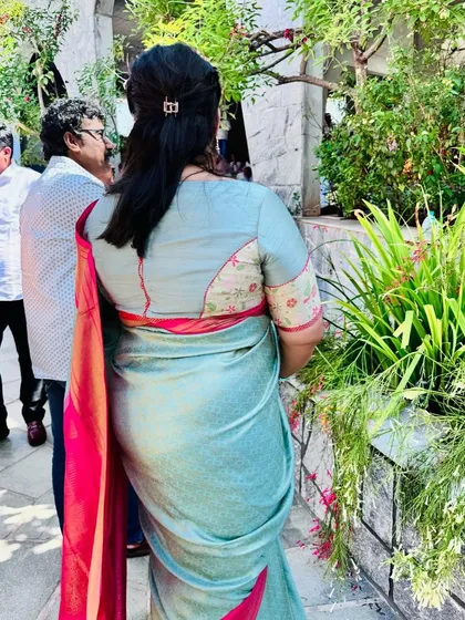 A back view of a client's blouse, showing a unique design with a floral patch on the sleeve and a contrasting pink border.