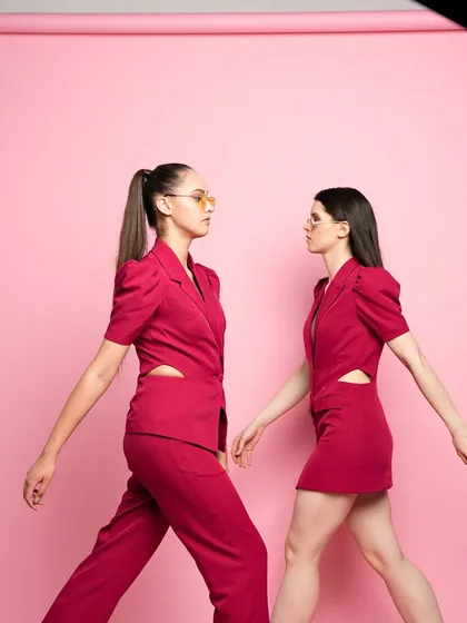 Two models in matching magenta outfits, one a pantsuit and the other a dress. This shot is about creating a powerful, unified brand image through coordinated styling.