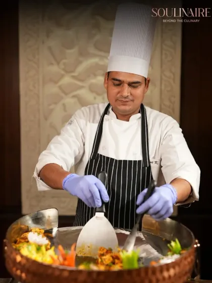 A chef at an interactive Tawa station, expertly mixing ingredients. Our live stations are a testament to our commitment to fresh, customized culinary experiences.