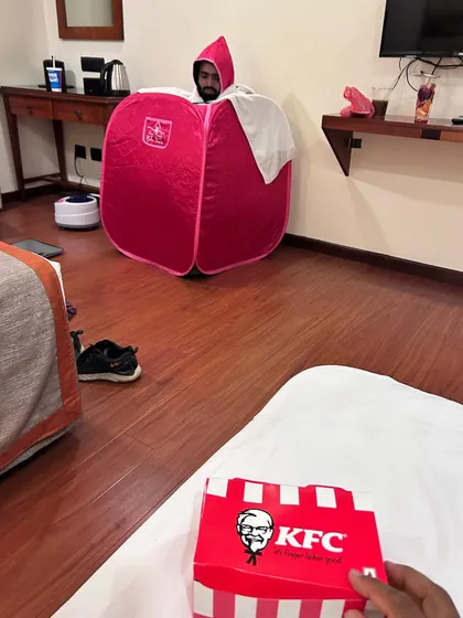 The two different worlds of a fight camp. While one fighter is in the final stages of a tough weight cut using a portable sauna, the team's support system is right there, even if it means eating KFC in the same room. This is the reality of the fight game.